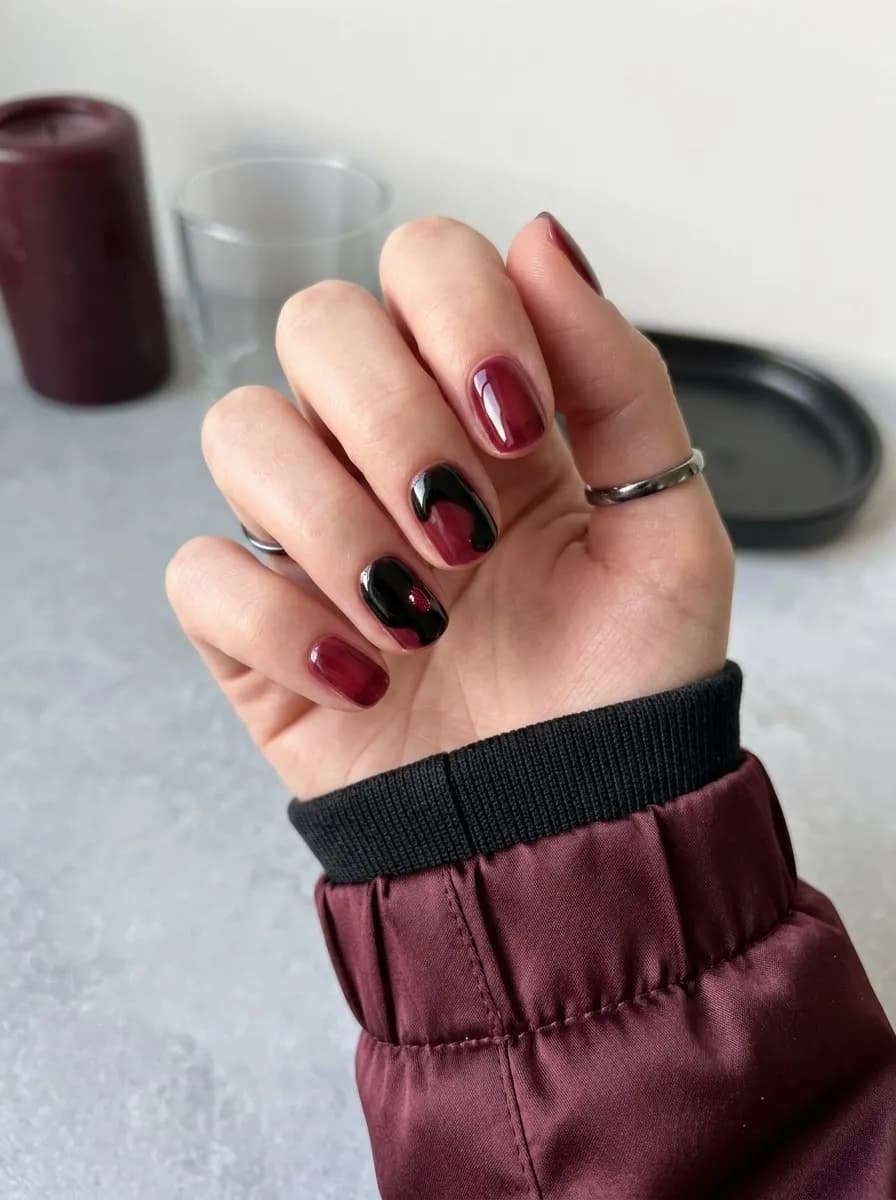 Short round nails with black French tips and tiny white ghost silhouettes on accent nails