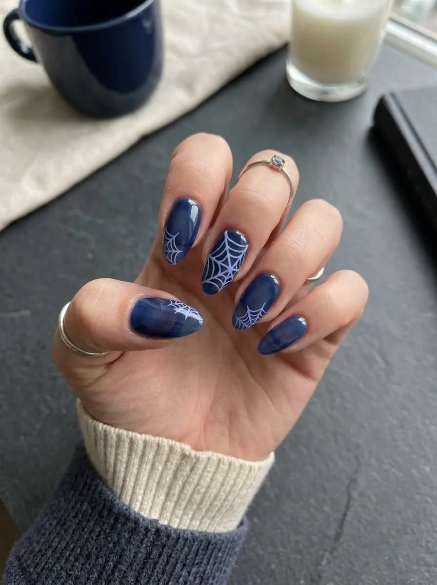 Navy blue almond nails with white spider web designs