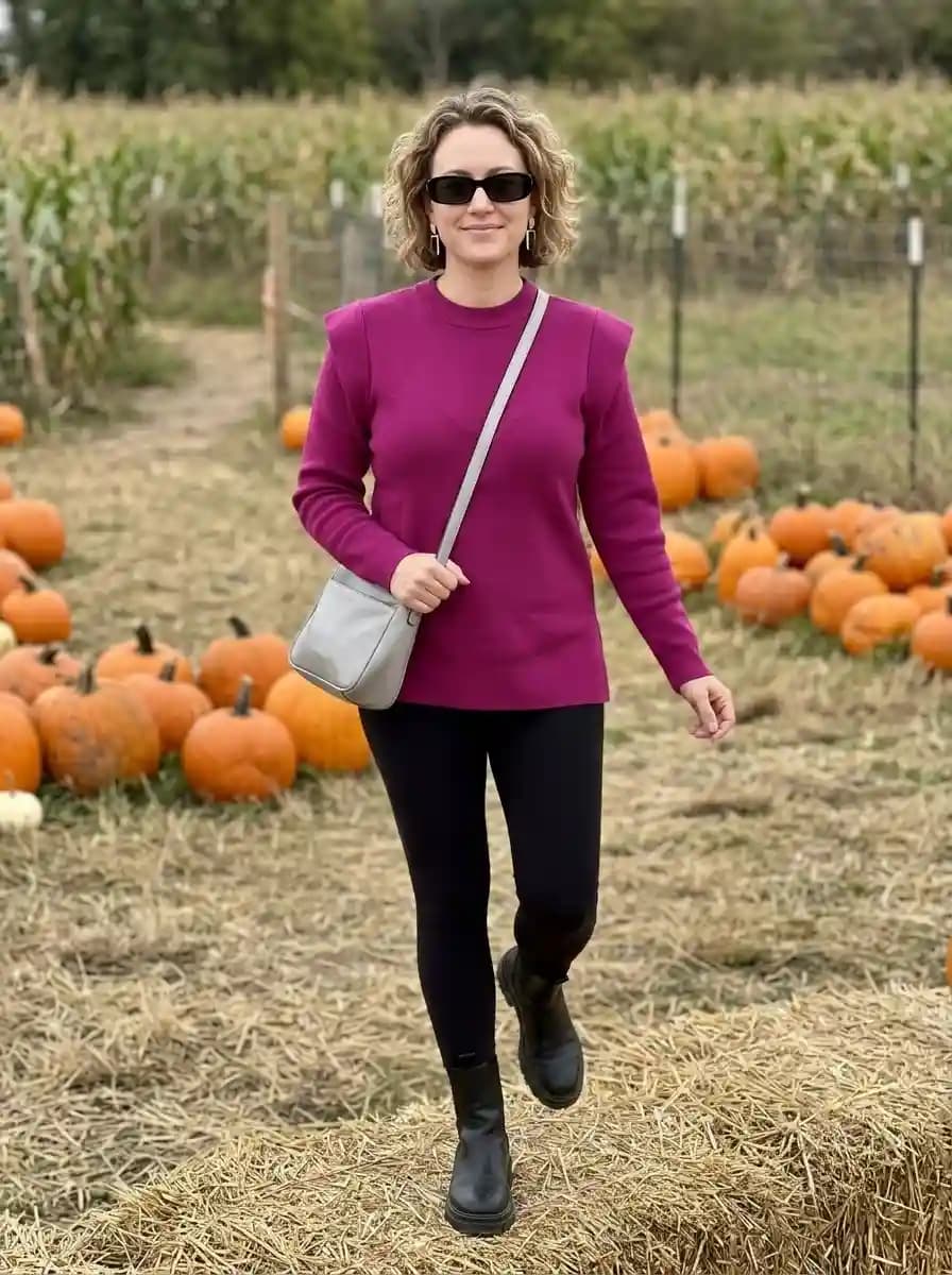 Berry pink sweater with black leggings, chunky Chelsea boots, and silver crossbody bag
