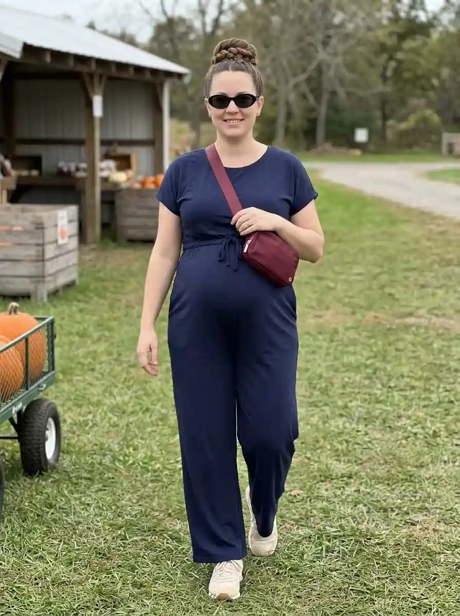 Navy wide-leg drawstring jumpsuit with white sneakers and burgundy belt bag