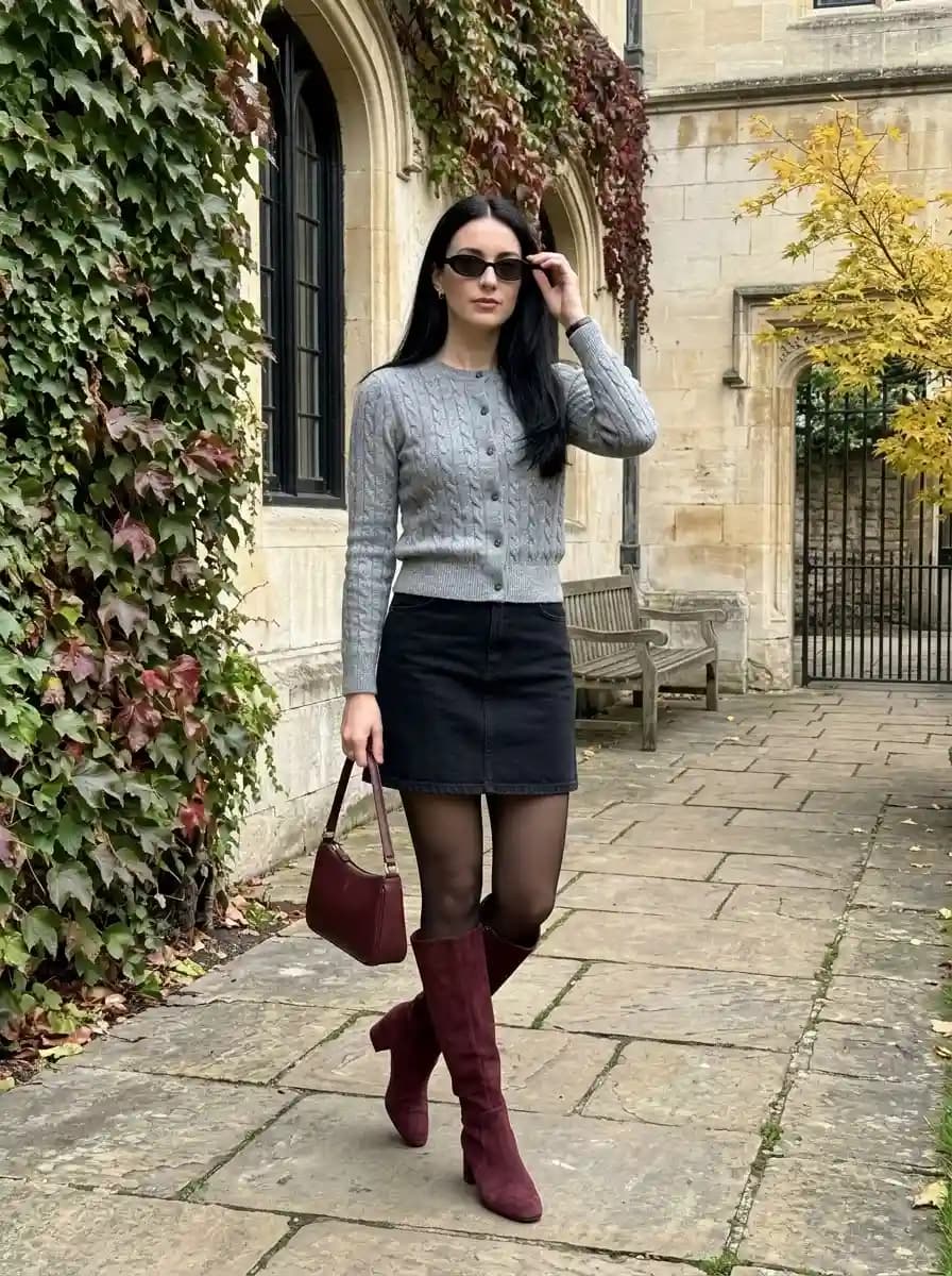 Grey cable-knit cardigan with dark denim mini skirt and burgundy boots