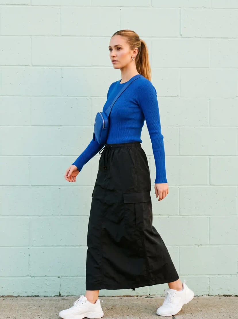 Cobalt blue ribbed knit long-sleeve top, black cargo maxi skirt, white sneakers, and blue crossbody bag