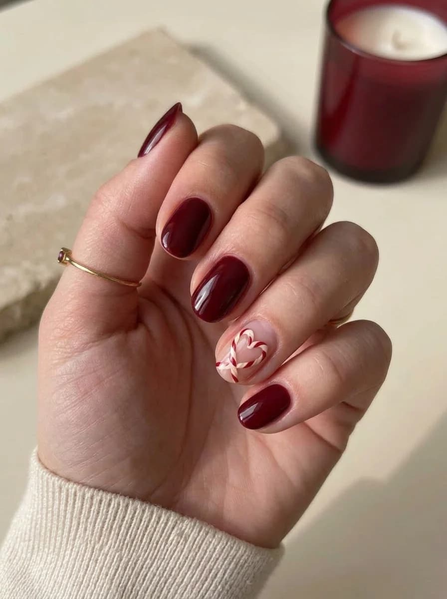 Deep red nails with candy cane heart accent nail