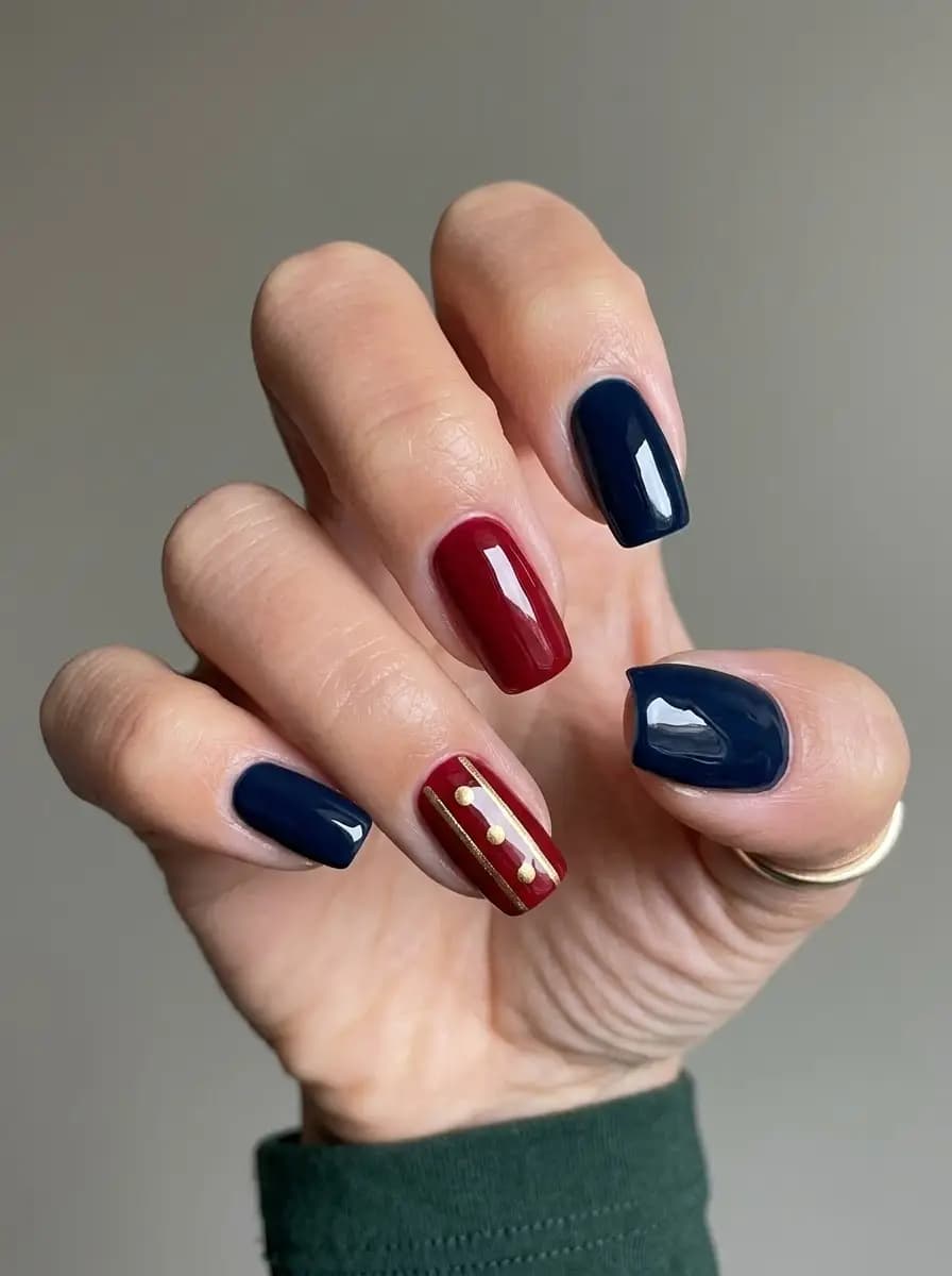 Navy blue, burgundy, and gold Christmas nails with tailored stripe and dot accents