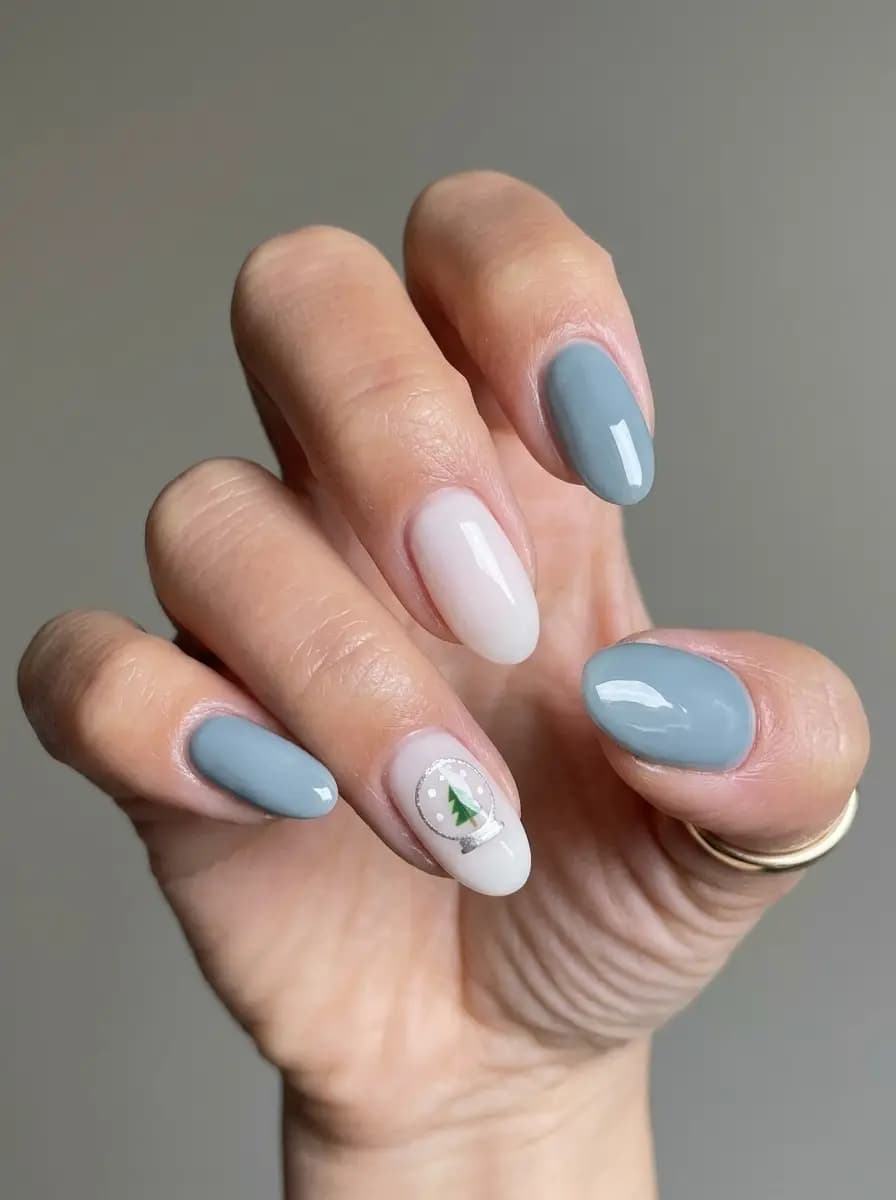 Icy blue snow globe Christmas nails with creamy white accents and miniature Christmas tree inside globe