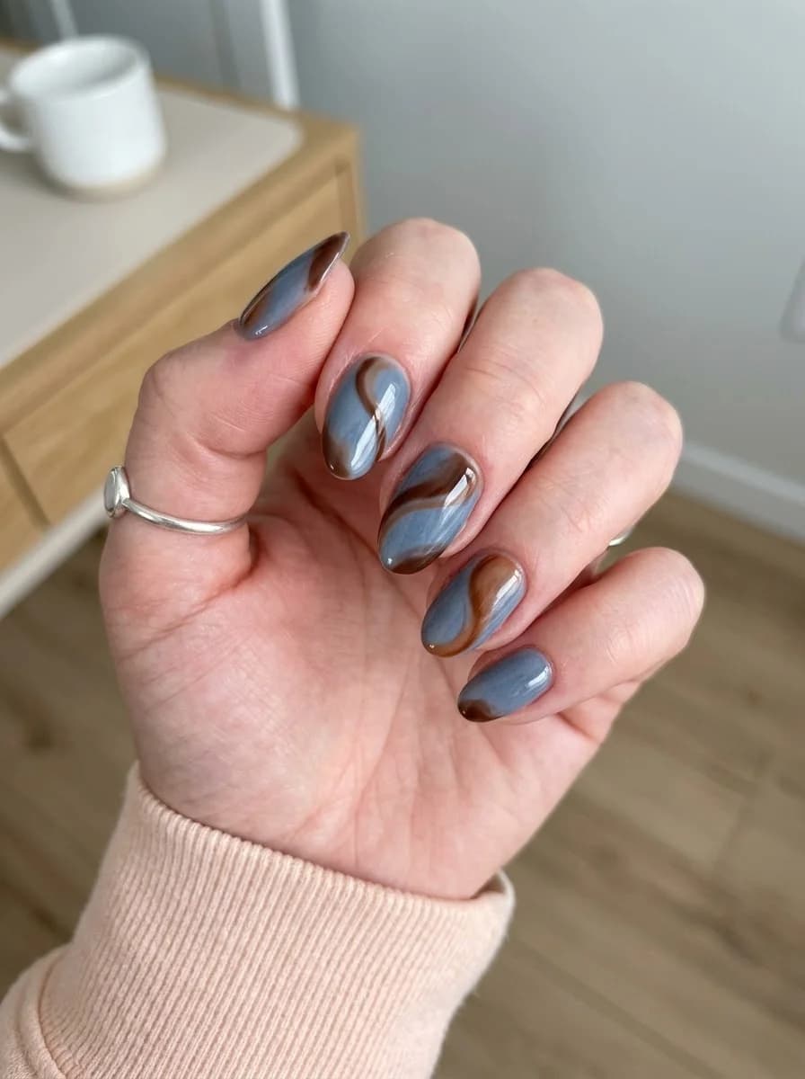 Short nails with marble swirls of cool blue-grey and warm chocolate brown