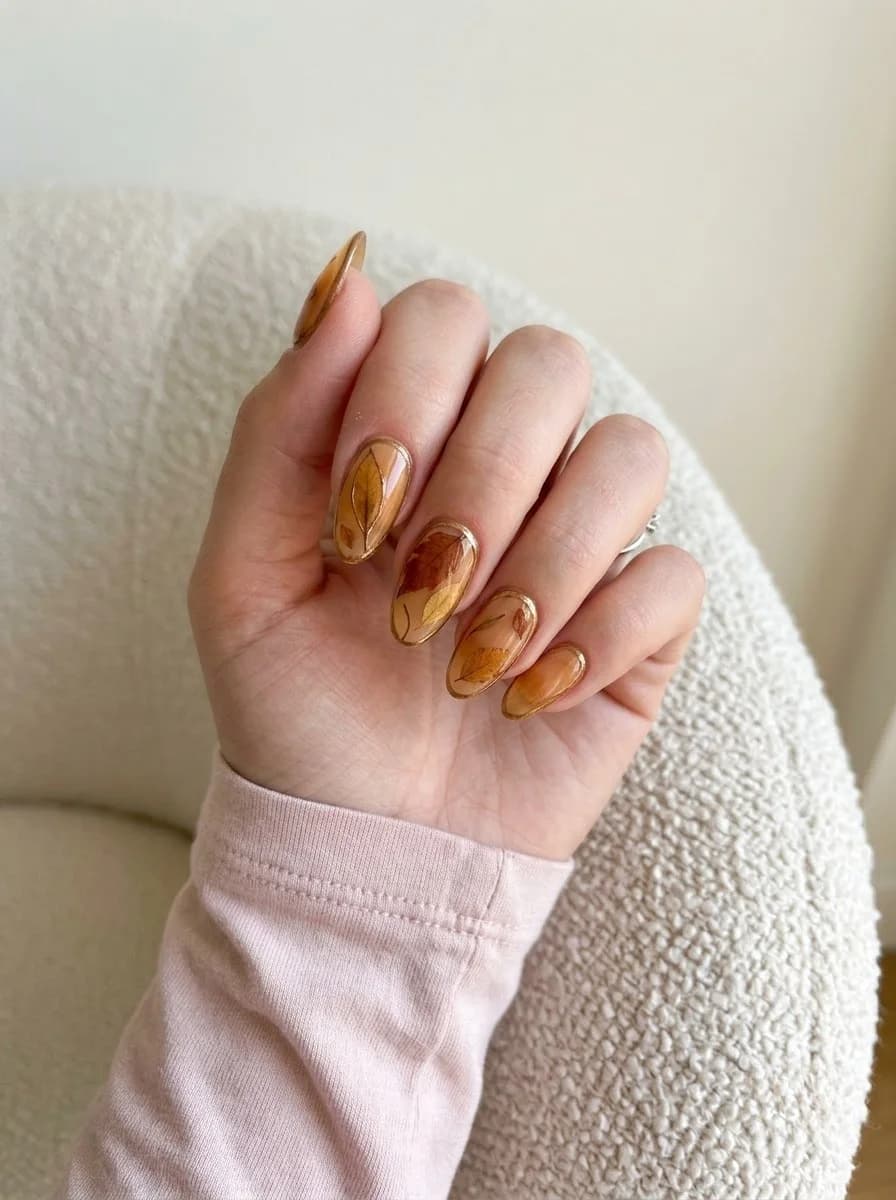 Short translucent amber nails with floating golden and rust-colored pressed autumn leaf artwork