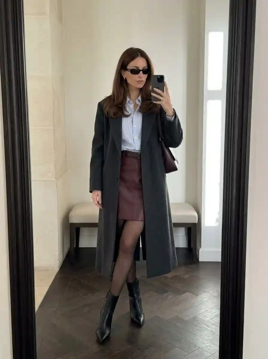 Blue-and-white striped button-down shirt with burgundy leather mini skirt and long charcoal grey coat