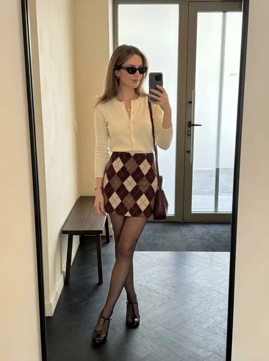 Cream fitted V-neck cardigan with burgundy argyle patterned mini skirt and black Mary Jane heels
