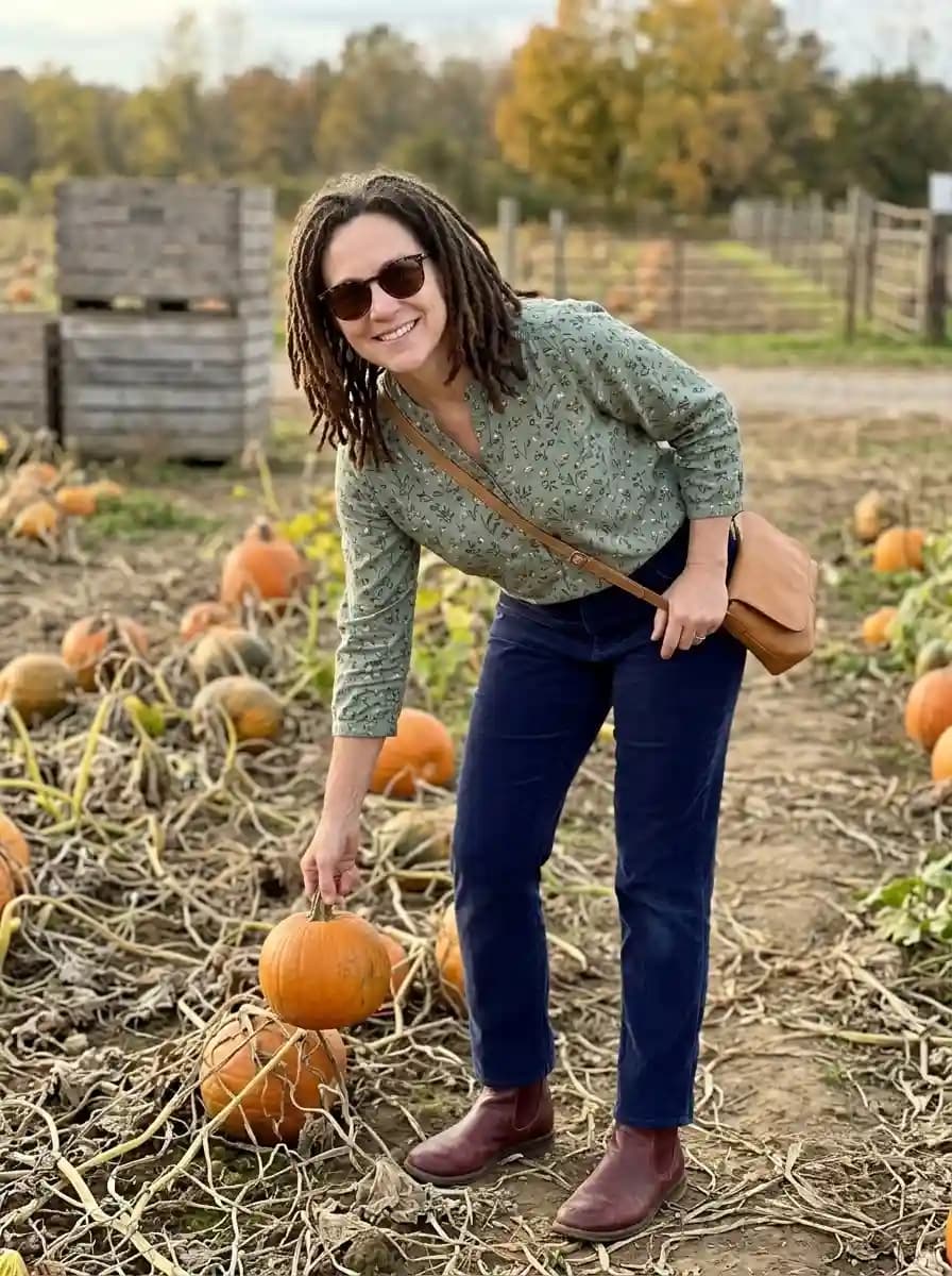 Sage green floral blouse with deep navy pants, burgundy ankle boots, and caramel crossbody bag