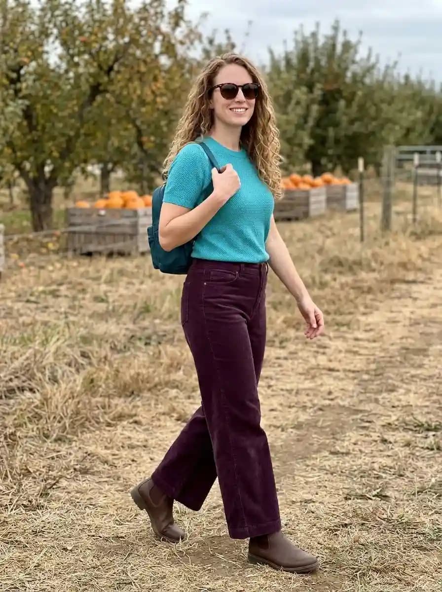 Turquoise short-sleeve knit top with plum corduroy pants and brown ankle boots