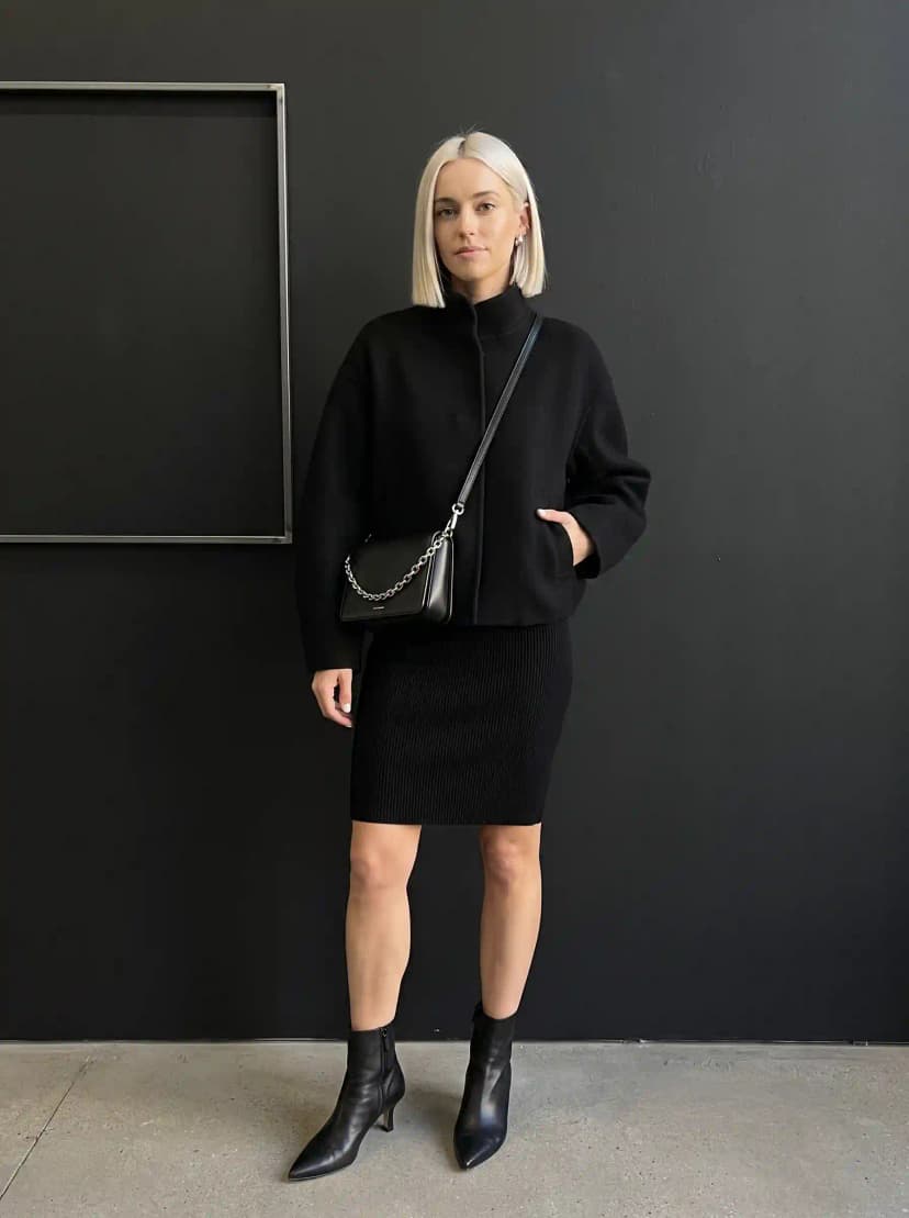 Black cropped mock-neck jacket, black ribbed mini skirt, and black ankle boots